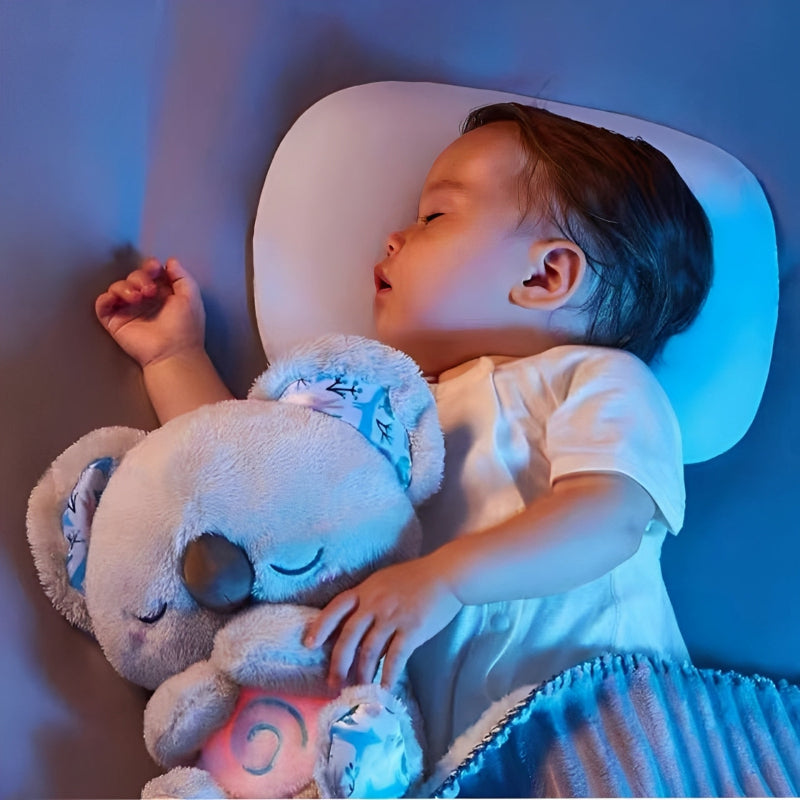 Baby sleeping with a blue koala in a dimly lit room