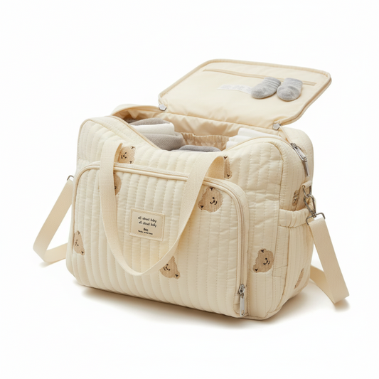 Beige quilted diaper bag with open top showing baby items on a white background