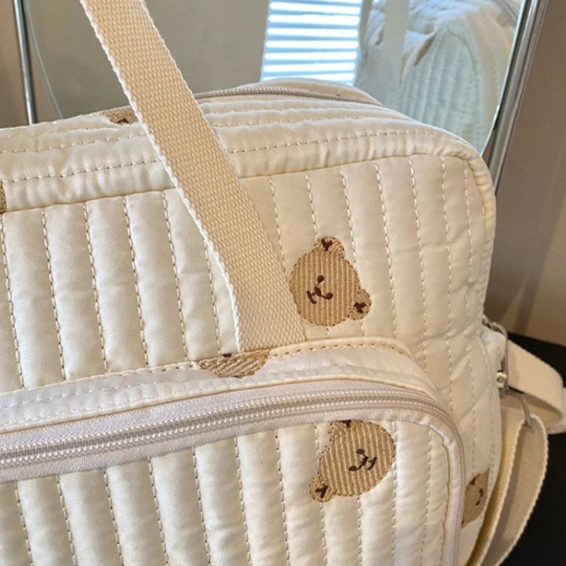 Quilted beige bag with embroidered bear designs on a neutral background