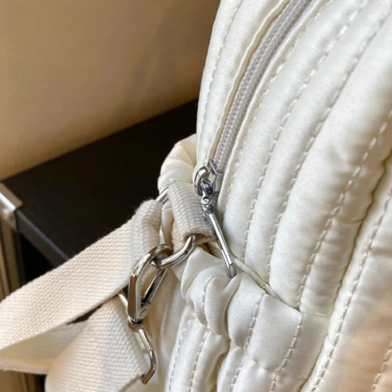 Close-up of a beige quilted handbag with a metal clasp.