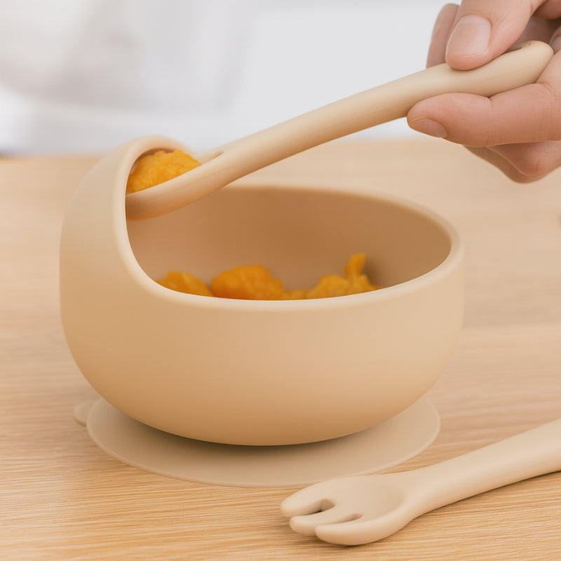 Beige bowl with spoon and fork on a wooden surface
